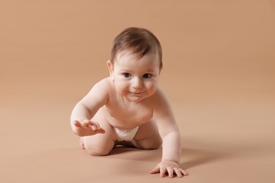 Photo of Cute little baby crawling on beige background