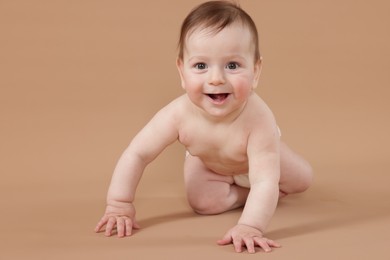 Photo of Cute little baby crawling on beige background