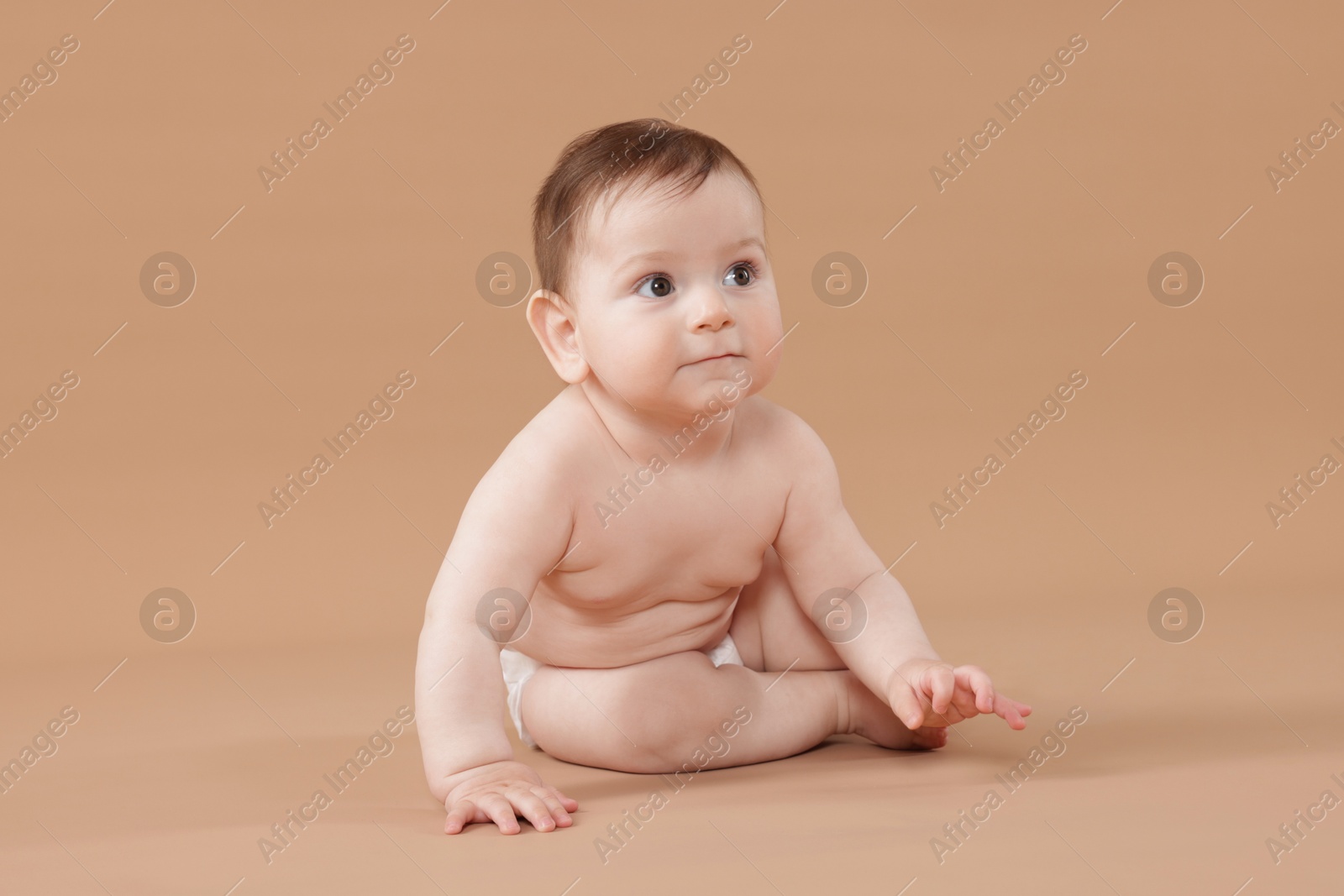 Photo of Cute little baby in diaper sitting on beige background