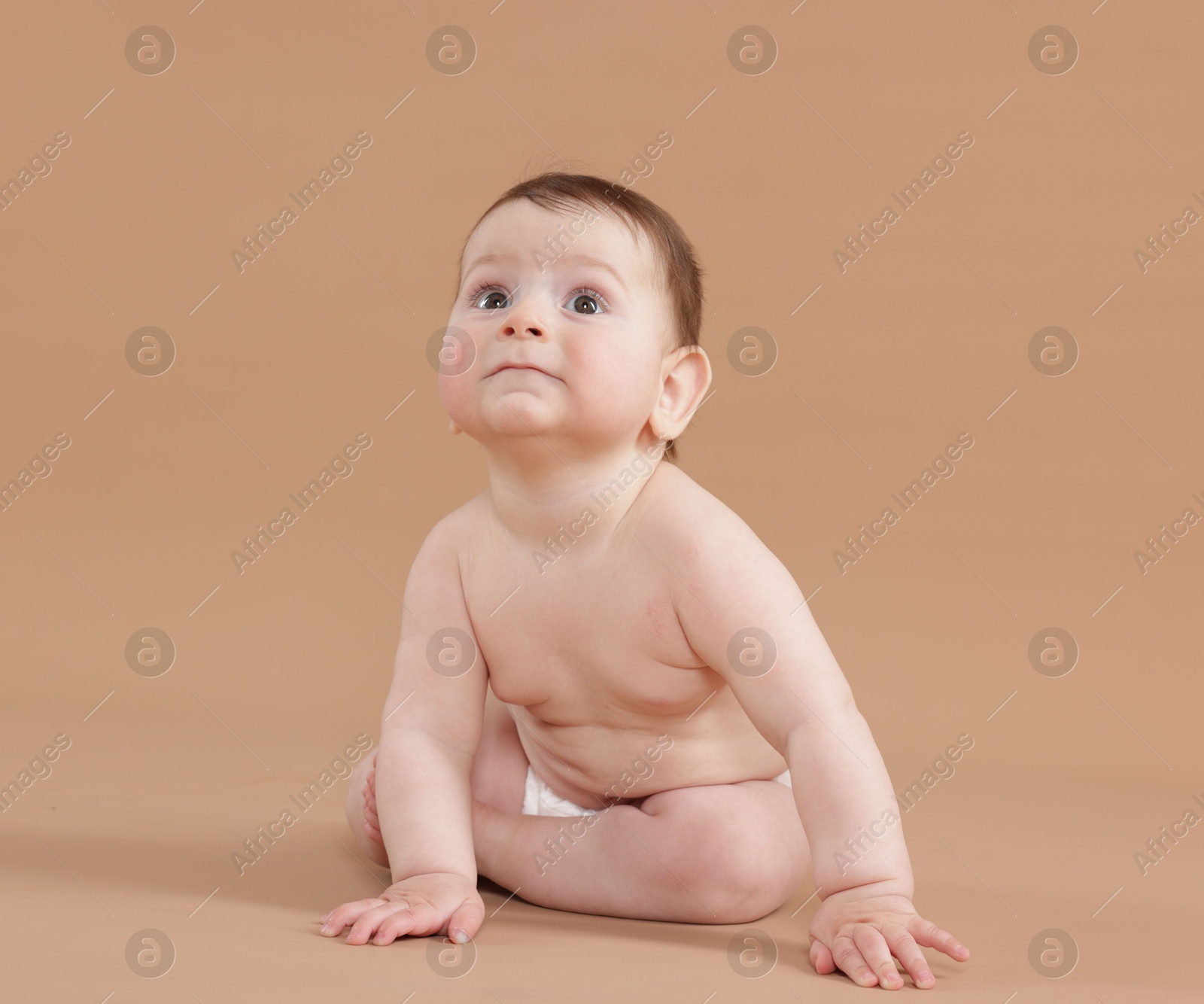 Cute little baby in diaper sitting on beige background Photo of Cute little baby in diaper sitting on beige background