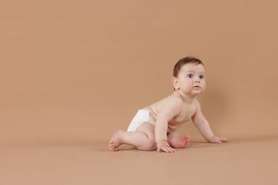 Photo of Cute little baby crawling on beige background. Space for text