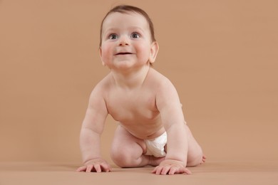 Photo of Cute little baby crawling on beige background