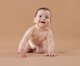 Photo of Cute little baby crawling on beige background