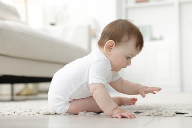 Photo of Cute little baby sitting on floor at home