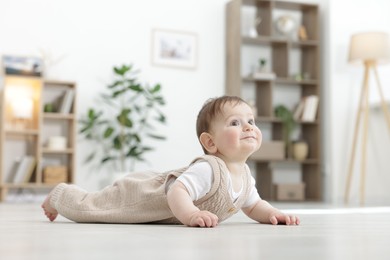 Photo of Cute little baby crawling on floor at home. Space for text