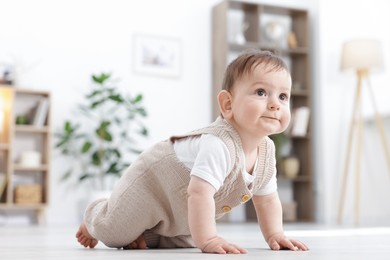 Photo of Cute little baby crawling on floor at home. Space for text