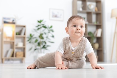 Photo of Cute little baby crawling on floor at home. Space for text