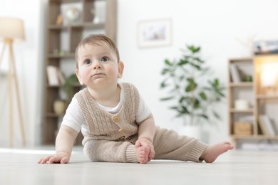 Photo of Cute little baby crawling on floor at home. Space for text