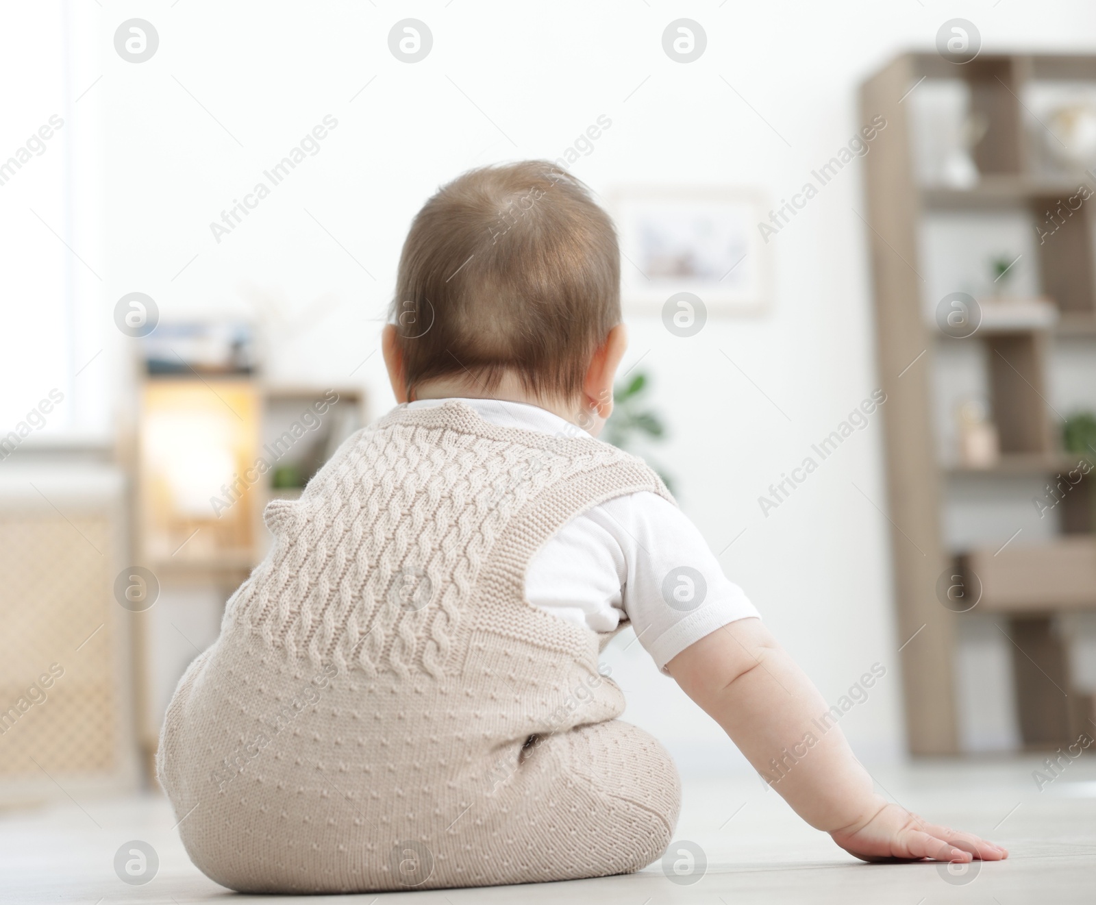 Cute little baby sitting on floor at home, back view Photo of Cute little baby sitting on floor at home, back view