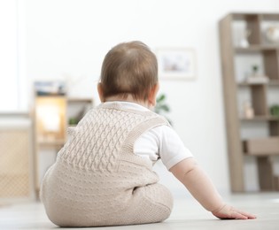 Photo of Cute little baby sitting on floor at home, back view