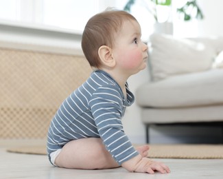 Photo of Cute little baby sitting on floor at home