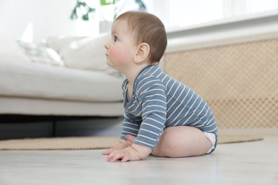 Photo of Cute little baby sitting on floor at home
