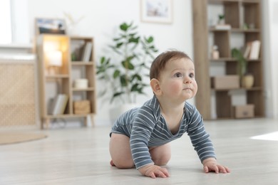 Photo of Cute little baby crawling on floor at home. Space for text