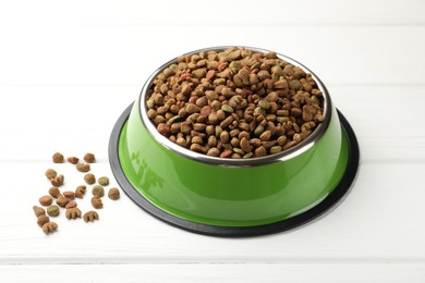 Photo of Dry pet food in feeding bowl on white wooden background, closeup