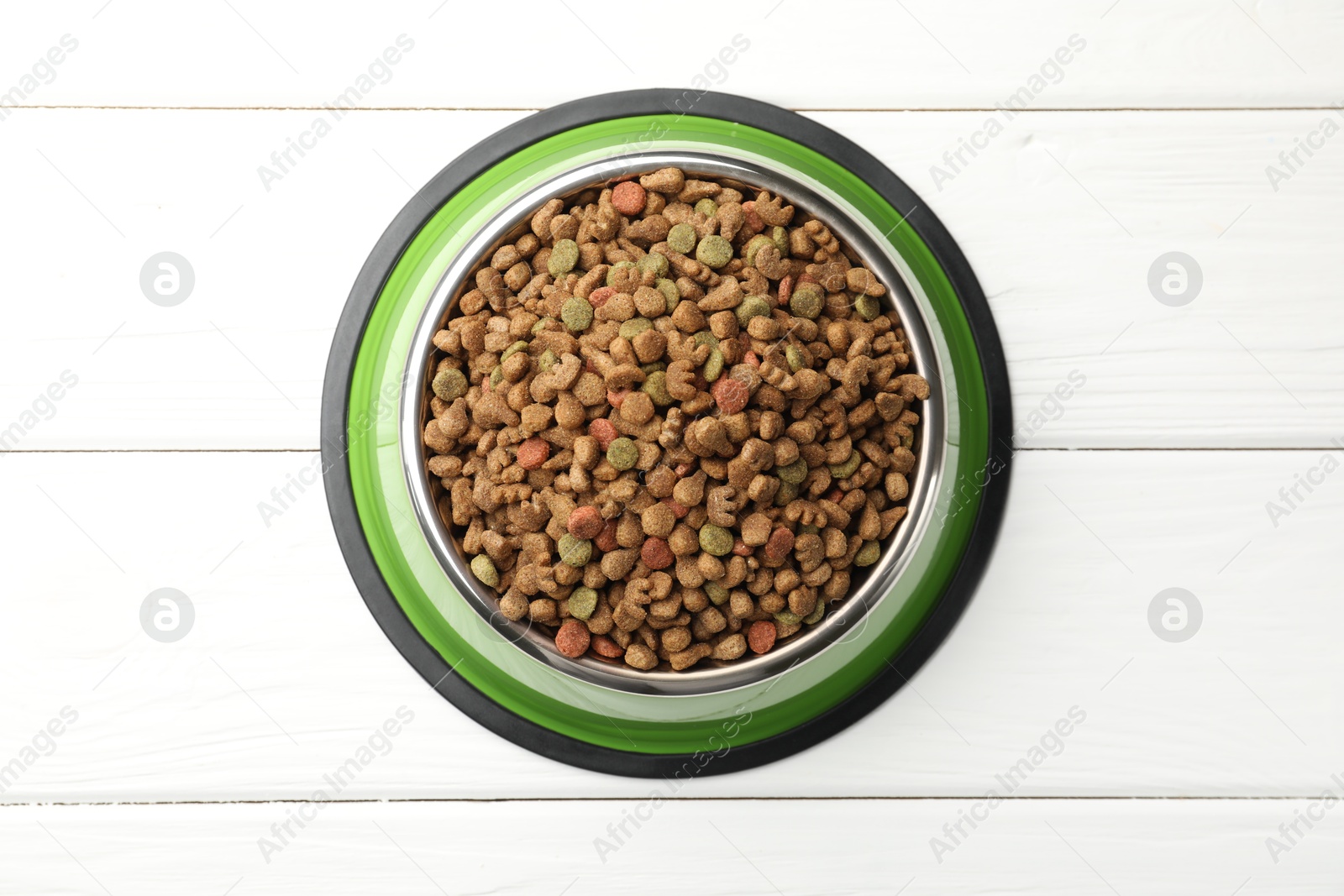 Dry pet food in feeding bowl on white wooden background, top view Photo of Dry pet food in feeding bowl on white wooden background, top view