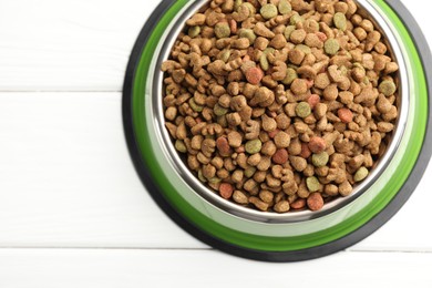 Photo of Dry pet food in feeding bowl on white wooden background, top view