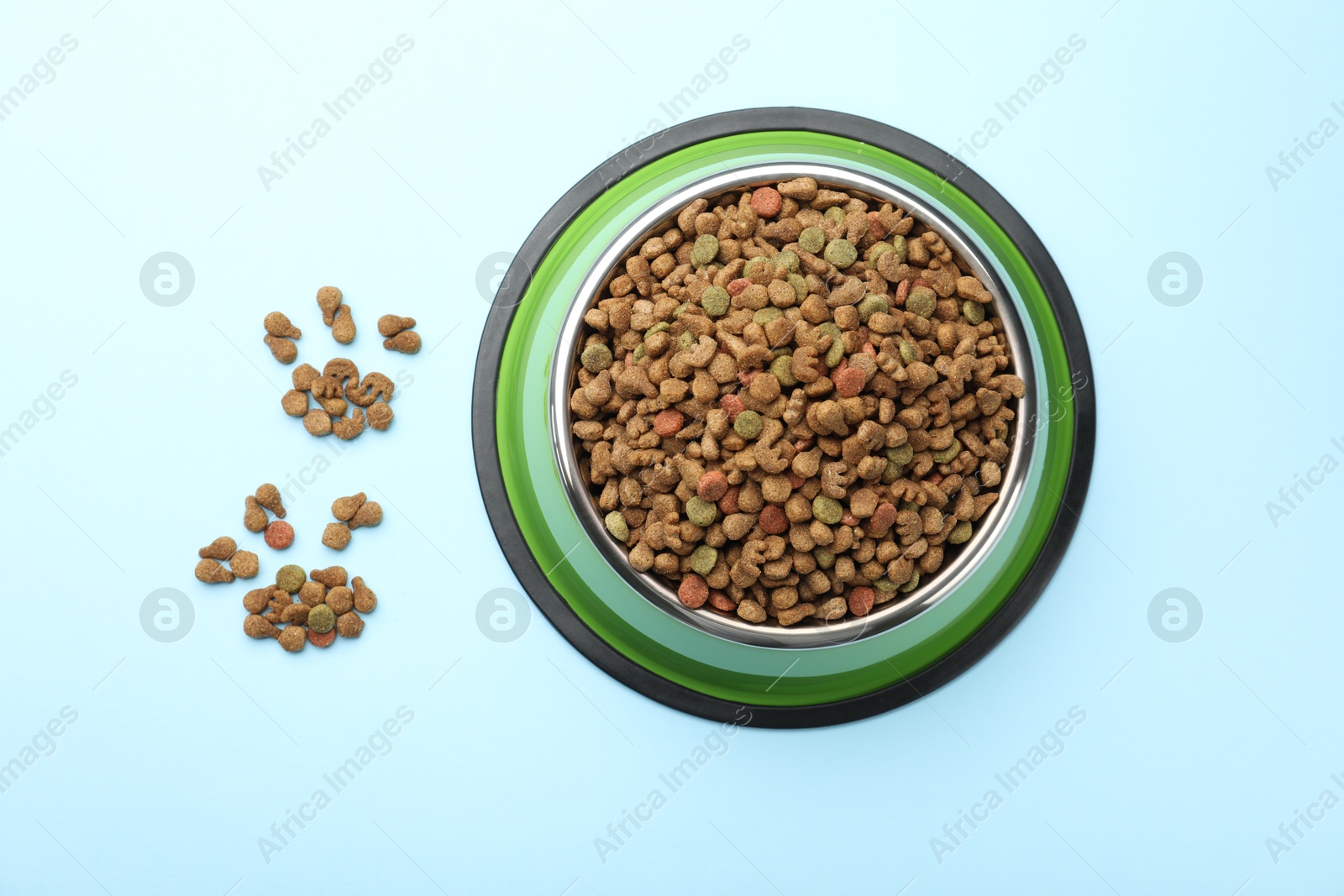 Dry pet food in feeding bowl on light blue background, top view Photo of Dry pet food in feeding bowl on light blue background, top view