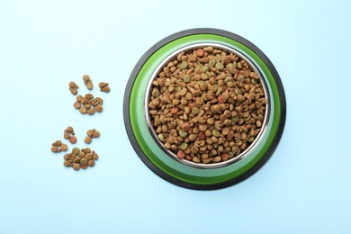 Photo of Dry pet food in feeding bowl on light blue background, top view
