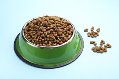 Photo of Dry pet food in feeding bowl on light blue background