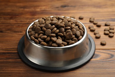 Photo of Dry pet food in feeding bowl on wooden background, closeup