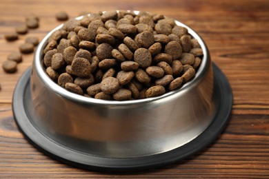 Photo of Dry pet food in feeding bowl on wooden background, closeup