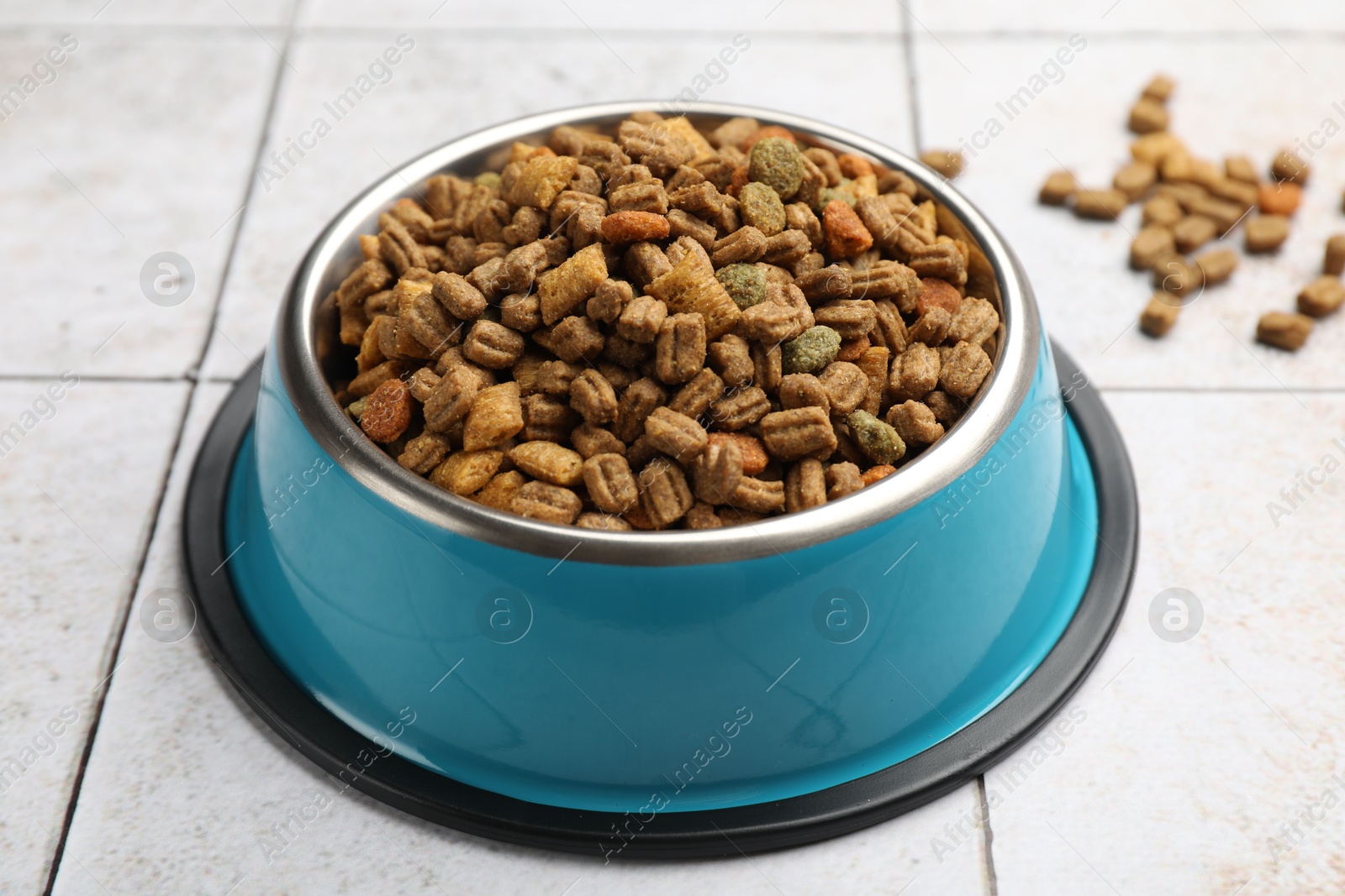 Dry pet food in feeding bowl on light tiled background, closeup Photo of Dry pet food in feeding bowl on light tiled background, closeup