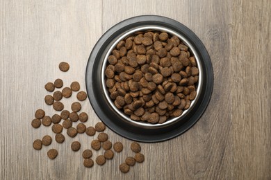 Photo of Dry pet food in feeding bowl on wooden background, top view