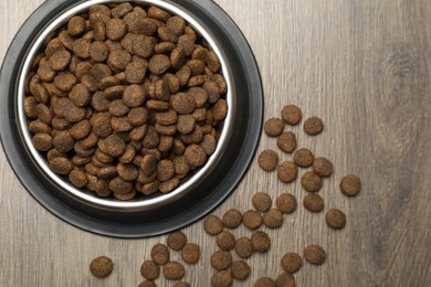 Photo of Dry pet food in feeding bowl on wooden background, top view