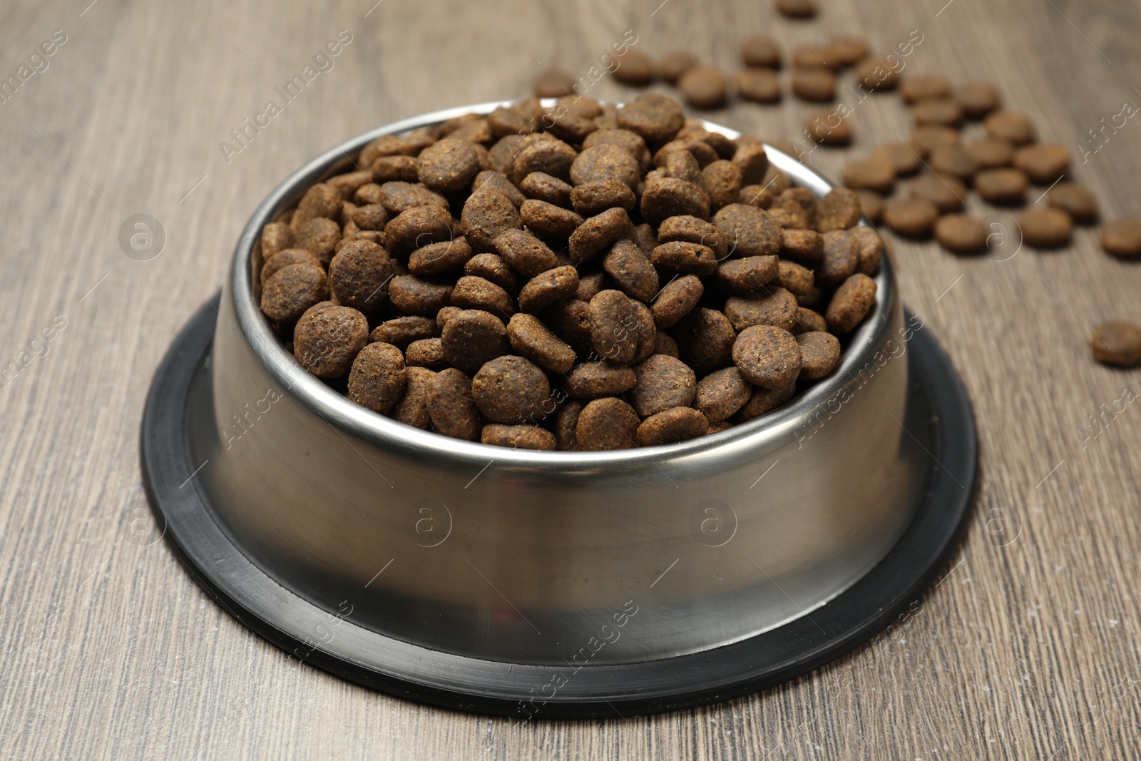 Dry pet food in feeding bowl on wooden background, closeup Photo of Dry pet food in feeding bowl on wooden background, closeup