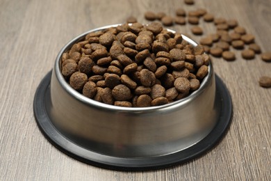 Photo of Dry pet food in feeding bowl on wooden background, closeup
