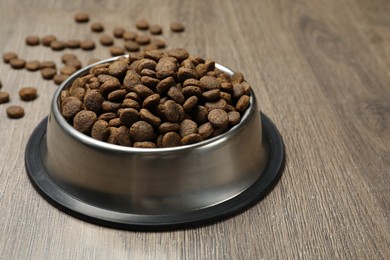 Photo of Dry pet food in feeding bowl on wooden background, closeup