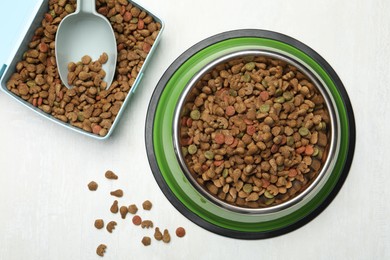 Photo of Dry pet food in feeding bowl, container and scoop on light background, flat lay