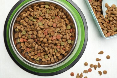 Photo of Dry pet food in feeding bowl, container and scoop on light background, flat lay