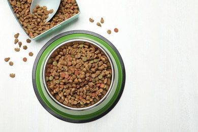 Photo of Dry pet food in feeding bowl, container and scoop on light background, flat lay. Space for text