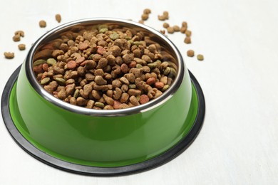 Photo of Dry pet food in feeding bowl on light background, closeup