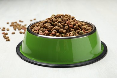 Photo of Dry pet food in feeding bowl on light background, closeup