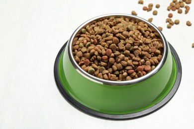 Photo of Dry pet food in feeding bowl on light background, closeup