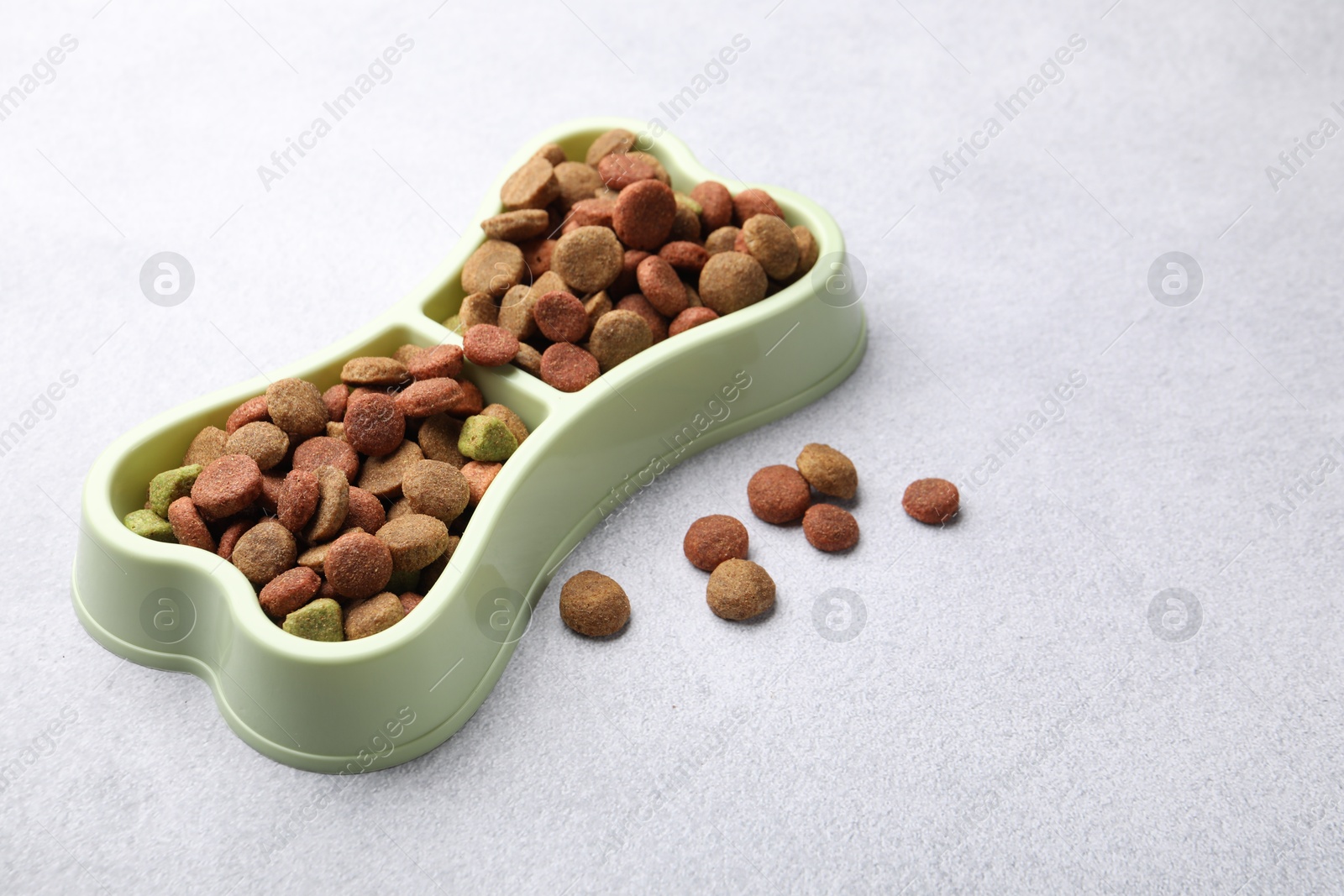 Dry pet food in feeding bowl on gray background Photo of Dry pet food in feeding bowl on gray background