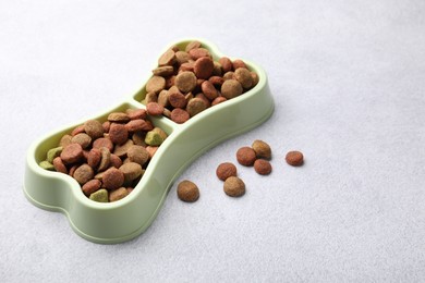 Photo of Dry pet food in feeding bowl on gray background
