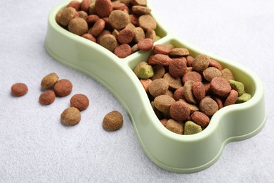 Photo of Dry pet food in feeding bowl on gray background, closeup
