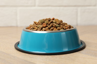 Photo of Dry pet food in feeding bowl on floor, closeup