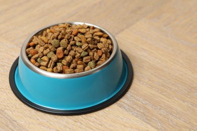 Photo of Dry pet food in feeding bowl on wooden background, closeup