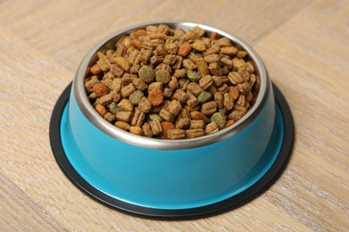 Photo of Dry pet food in feeding bowl on wooden background, closeup