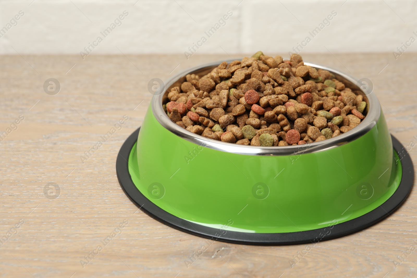 Dry pet food in feeding bowl on floor, closeup Photo of Dry pet food in feeding bowl on floor, closeup