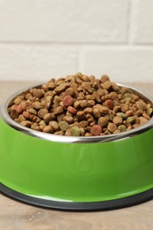 Photo of Dry pet food in feeding bowl on floor, closeup