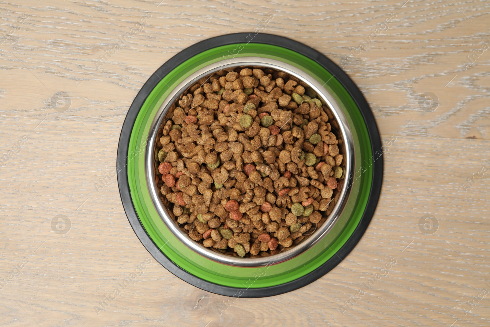 Dry pet food in feeding bowl on wooden background, top view Photo of Dry pet food in feeding bowl on wooden background, top view