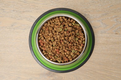Photo of Dry pet food in feeding bowl on wooden background, top view