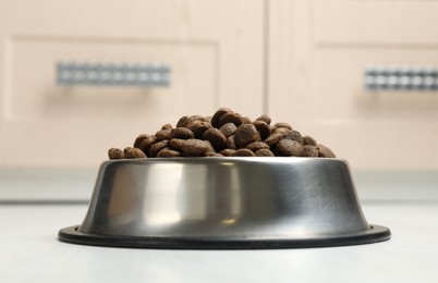 Photo of Dry pet food in feeding bowl on floor