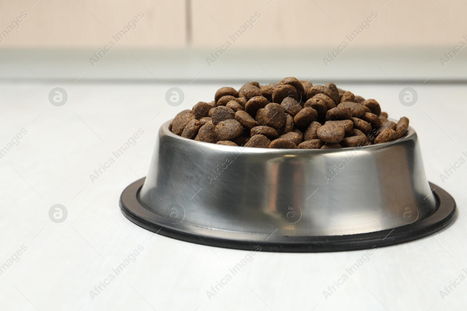Dry pet food in feeding bowl on floor Photo of Dry pet food in feeding bowl on floor