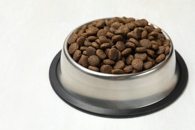 Photo of Dry pet food in feeding bowl on light background, closeup